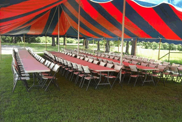 black and white outside tent with long white tables underneath and white chairs