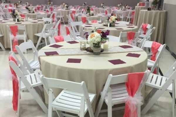 white table and chairs for reception with pink ribbons on chairs