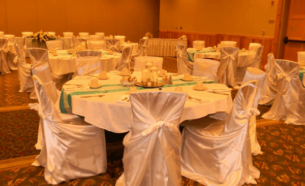 white silk covered chairs at white circular table cloth for wedding reception
