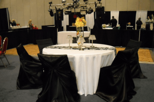 black silk covered chairs around a white circular table cloth for event