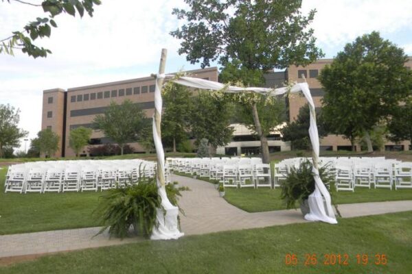 white arch in front of white chairs for wedding ceremony on grass