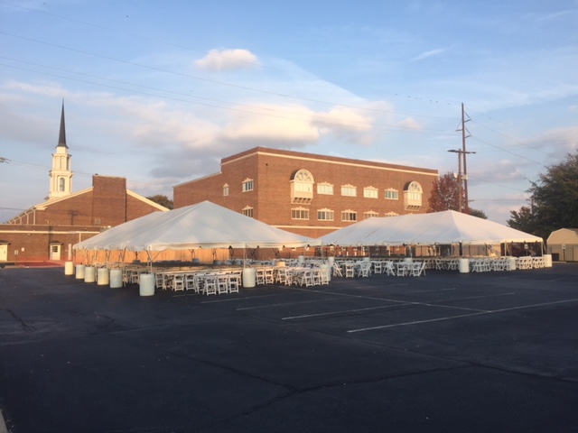 church parking lot with two large white tents and chairs and tables set up