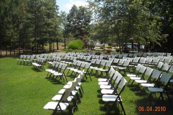 white chairs on grass beside trees for wedding ceremony